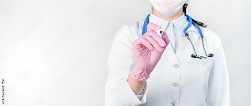 Cropped view of young female doctor in a white coat with stethoscope and pink sterile gloves pretends to write a text with marker. Medical concept. Copy space for your text. Cropped view of young female doctor in a white coat with stethoscope and pink sterile gloves pretends to write a text with marker. Medical concept. Copy space for your text.