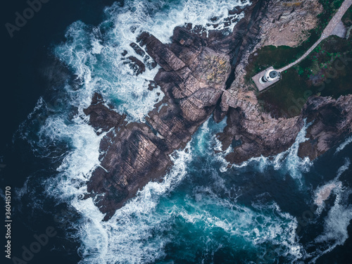 Aerial drone view of lighthouse and cliff with rough sea