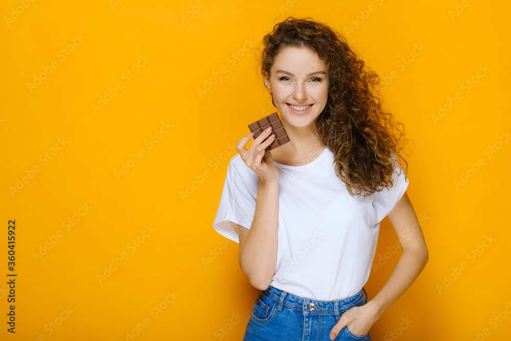 Happy girl with chocolate bar on yellow background Happy girl with chocolate bar on yellow background