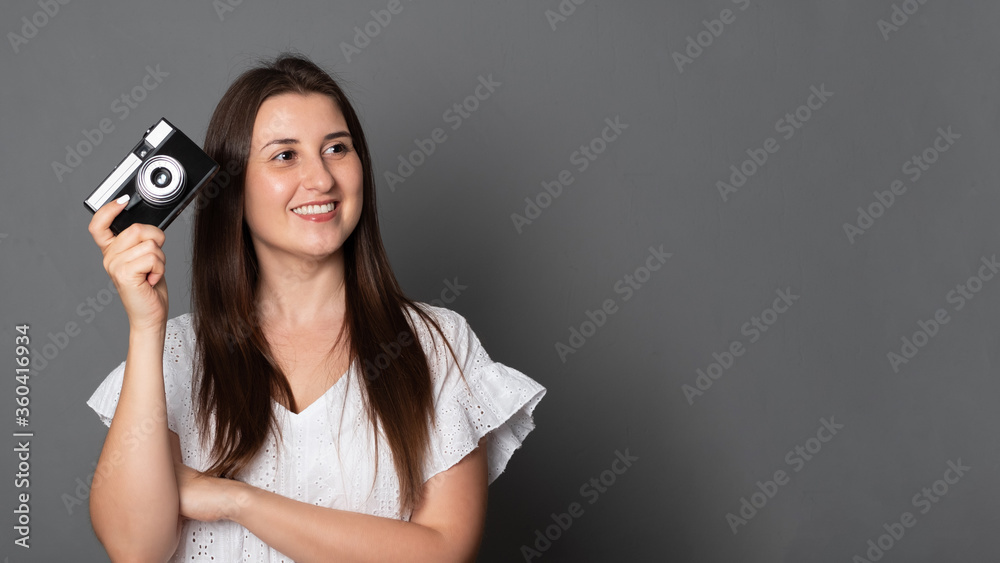 Smiling woman takes pictures with an old camera. Beautiful girl holds a camera. Smiling woman takes pictures with an old camera. Beautiful girl holds a camera.
