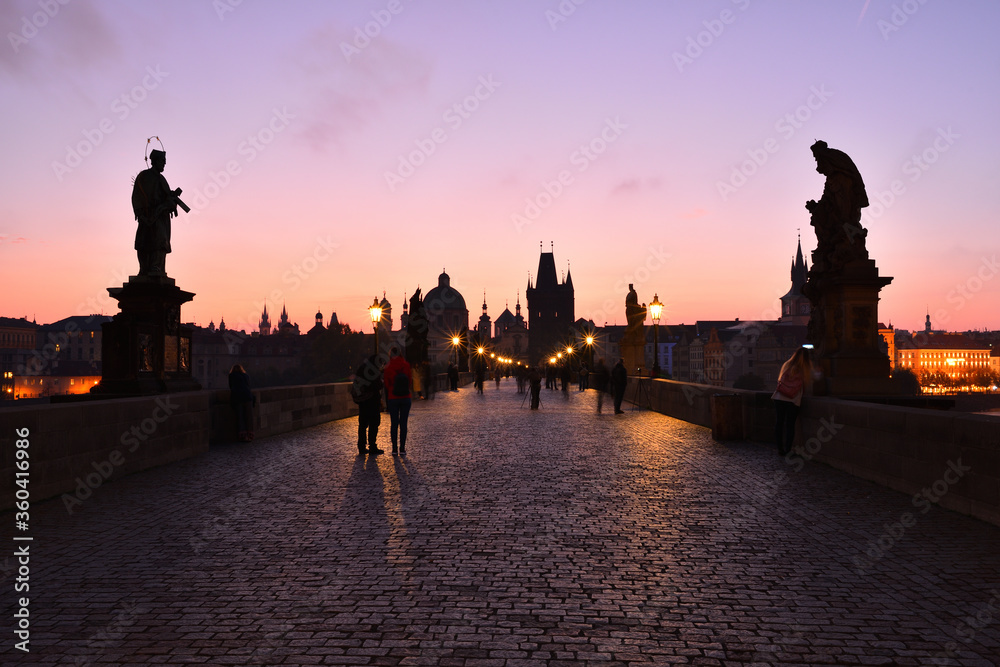 Charles Bridge in Prague Old Town. Silhouettes on ancient statues. Early morning. Sunrise.