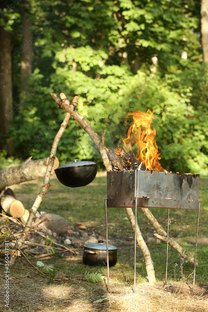 Cooking meat outdoors in a cast-iron pot. Summer outdoor activities. Camping family holiday. Food cooked on coals. Cooking meat outdoors in a cast-iron pot. Summer outdoor activities. Camping family holiday. Food cooked on coals.