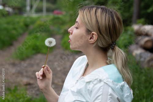 girl is blows away dandelion blowball