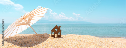 Canvas Print Small house and umbrella on sand, beach, blue sea and sky on blurred background