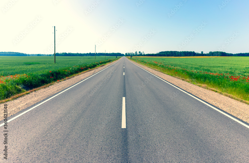 Asphalt road between agricultural fields of Latvia. Sunny summer bright day. Asphalt road between agricultural fields of Latvia. Sunny summer bright day.