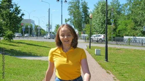 Cute teenage girl riding a skateboard in a city park. The concept of urban life and youth culture