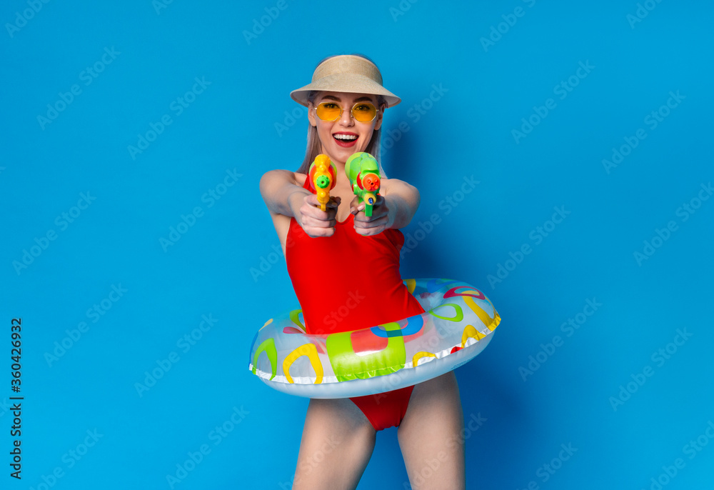 Joyful Millennial Girl In Swimsuit Playfully Aiming With Water Guns At Camera