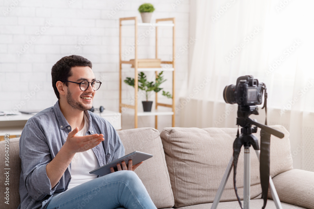 Confident young man recording on camera to blog. Speaking with enthusiasm Confident young man recording on camera to blog. Speaking with enthusiasm