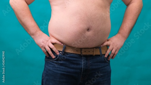 male with a big belly shows his fat on a green screen. The concept of healthy eating and losing weight, diet