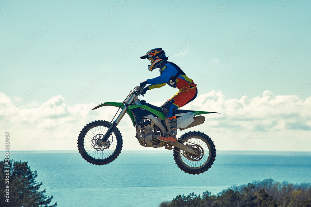 Extreme concept, challenge yourself. Extreme jump on a motorcycle on a background of blue sky with clouds. Copy space, all or nothing. Extreme concept, challenge yourself. Extreme jump on a motorcycle on a background of blue sky with clouds. Copy space, all or nothing.
