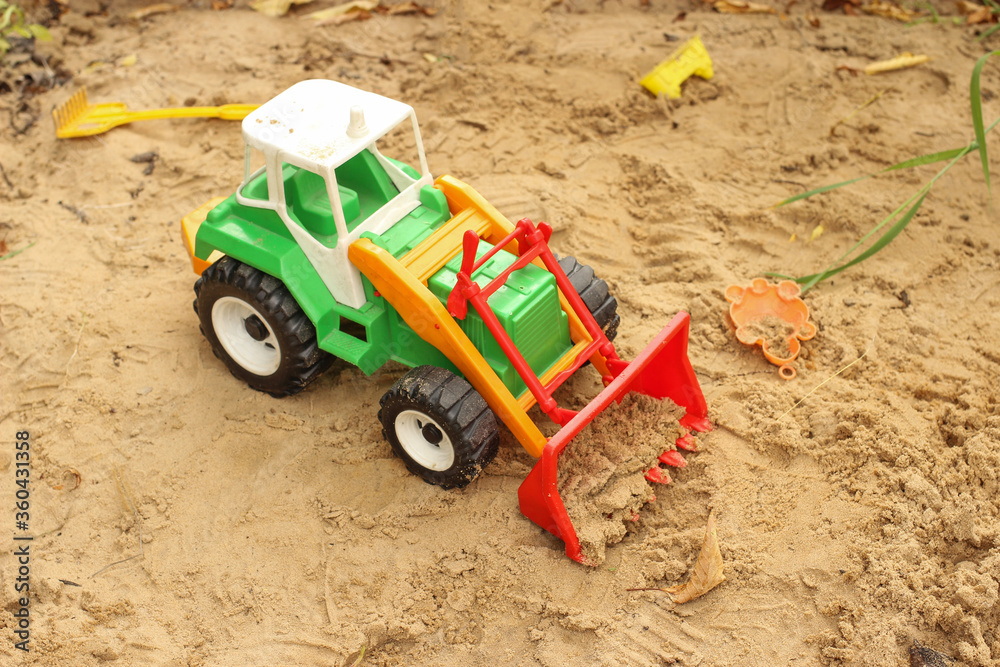 Toy tractor, excavator in the sandbox Toy tractor, excavator in the sandbox