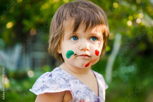 little girl is drawing. Young artist. Painting. Funny girl in the park. activity for children. funny girl painted her face. Dirty face 