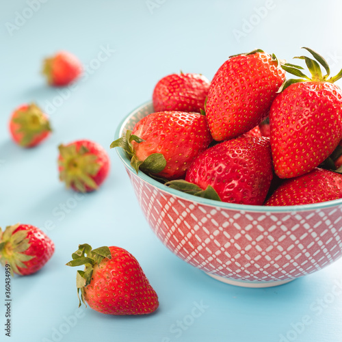 colorful ripe strawberries in a bright bowl on a blue background