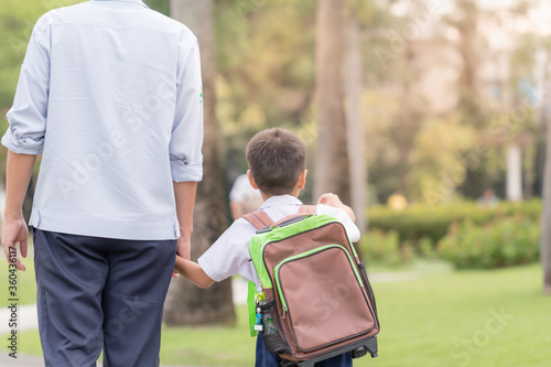 Asian young father holding hand his son walking to school in the morning
