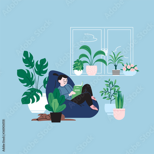 A girl staying home reading a book by the window sitting in the bean bag chair. A room full of plants.