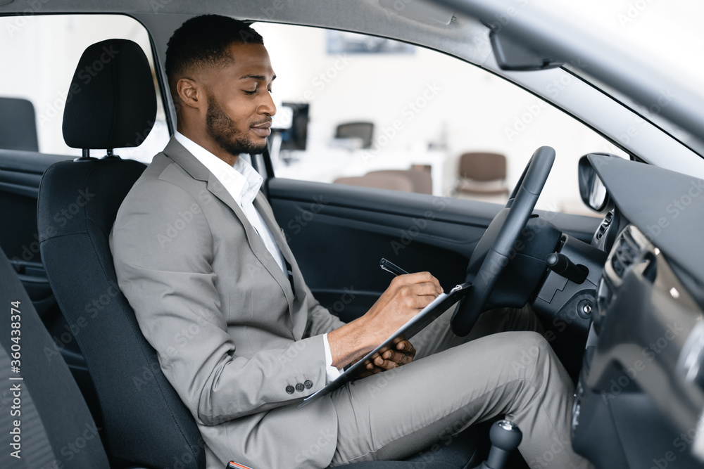 Dealer Taking Notes Sitting In Car Checking Automobile In Dealership Dealer Taking Notes Sitting In Car Checking Automobile In Dealership