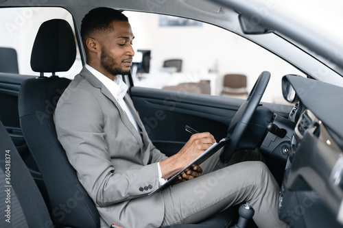 Dealer Taking Notes Sitting In Car Checking Automobile In Dealership © Prostock-studio