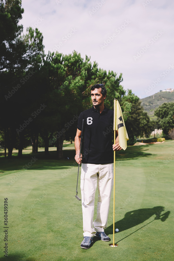 Full length portrait of handsome mature man playing golf at beautiful summer day on green course Full length portrait of handsome mature man playing golf at beautiful summer day on green course