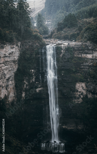 A waterfall in a forest surrounded by rocks and trees