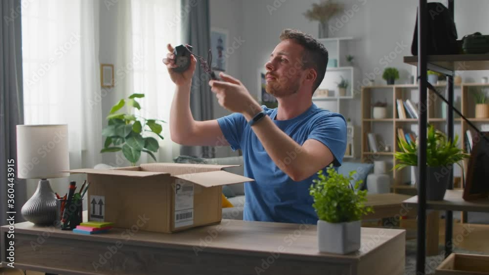 Handsome young man takes a computer mouse out of a cardboard box. Unpacking online purchases. Handsome young man takes a computer mouse out of a cardboard box. Unpacking online purchases.