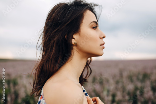 Fotografie Young brunette woman with long neck and bare shoulders, standing in an open field