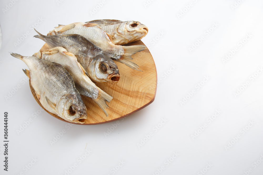 close up top corner shot of a bunch of five Russian dried salted vobla (Caspian Roach) fish on a wooden plate on a white background