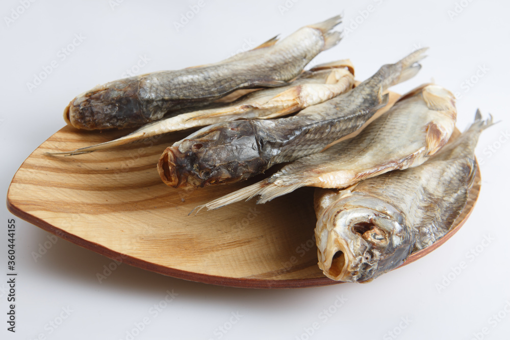 close up top corner shot of a bunch of five Russian dried salted vobla (Caspian Roach) fish on a wooden plate on a white background