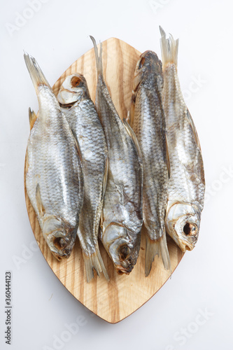 close up top view shot of a bunch of five Russian dried salted vobla (Caspian Roach) fish on a wooden plate on a white background photo