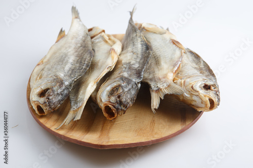 close up top corner shot of a bunch of five Russian dried salted vobla (Caspian Roach) fish on a wooden plate on a white background