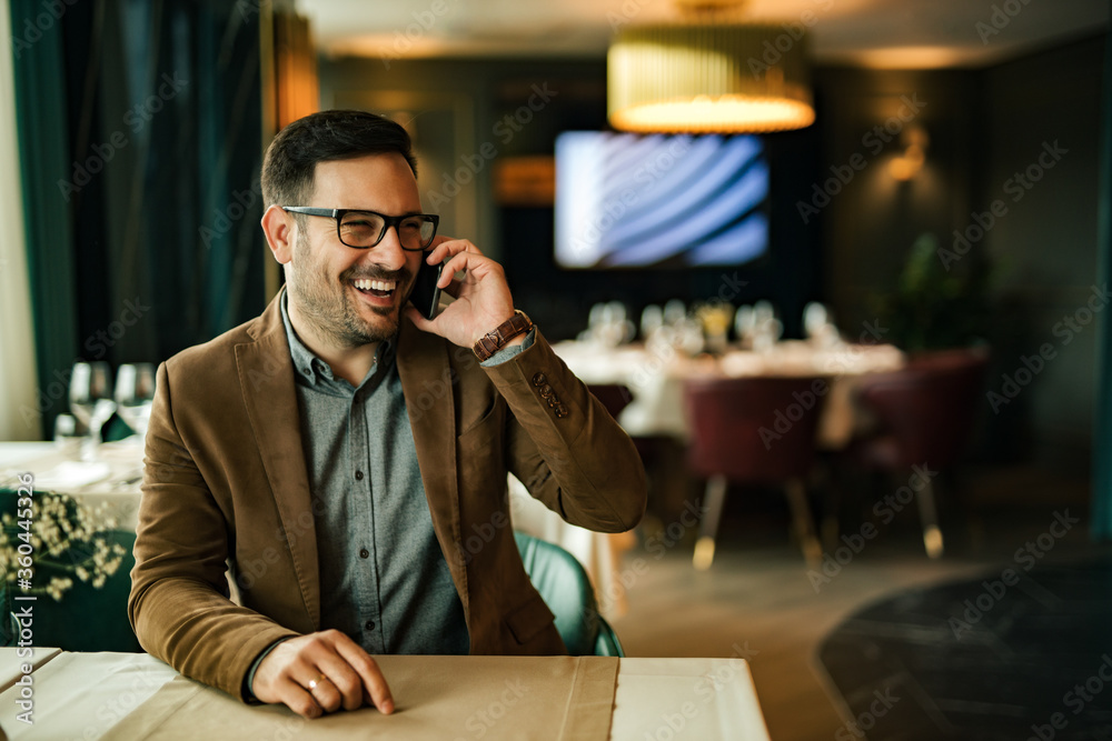 Smiling businessman having a phone call while sitting in the restaurant, portrait. Smiling businessman having a phone call while sitting in the restaurant, portrait.