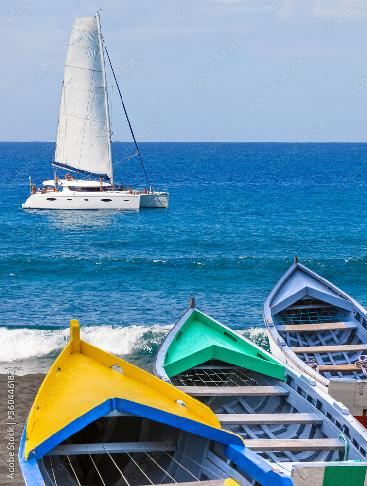 Foto de Barques de pêche sur plage et catamaran en mer, baie de Saint ...