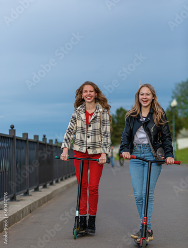 Teenage girls ride scooters in the evening