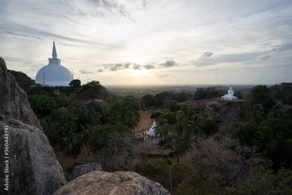 Aerial image of Mihintale Budhist temples during sunset with pagoda and Budha sculpture among trees