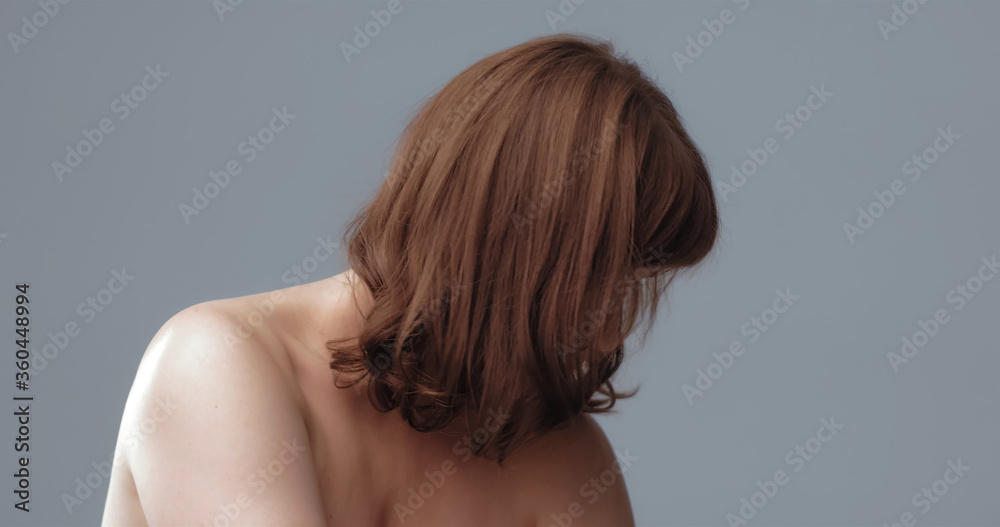 Depressed naked woman lowered her head, covering her face with hair. Pensive red-haired woman on gray background. Aging process concept. Lonely concept. Depressed naked woman lowered her head, covering her face with hair. Pensive red-haired woman on gray background. Aging process concept. Lonely concept.