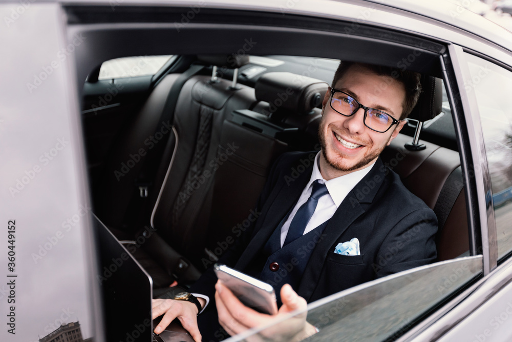 Businessman sitting in luxury car looking out of window