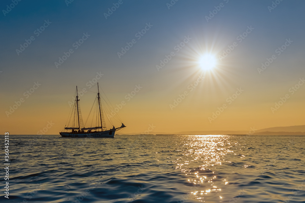 Fototapeta premium beautiful sailing yacht on the horizon at sunset, beautiful natural landscape