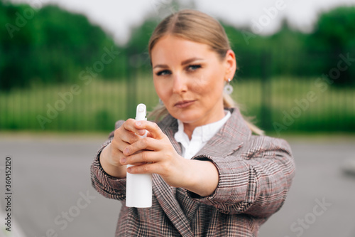 Stylish girl in an elegant suit holds bottle with an antiseptic. The concept of health care during a pandemic photo