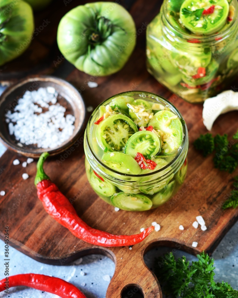 Fermented Pickled green tomatoes with horseradish and hot pepper on a gray background Fermented Pickled green tomatoes with horseradish and hot pepper on a gray background