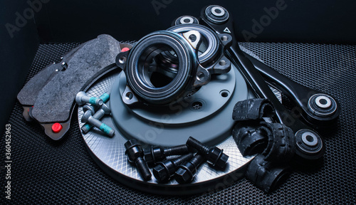 lot of car parts running gear: brake disc, pads and hub bearing with fasteners, isolated on a black background.