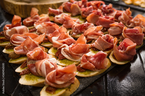 Bruschettas with ham or parma. Snack baguette with meat. Antipasto concept. Catering food concept. Close up shot.