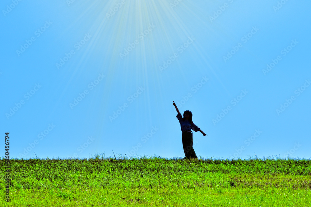 踊りながら日差しを浴びる女性のシルエット