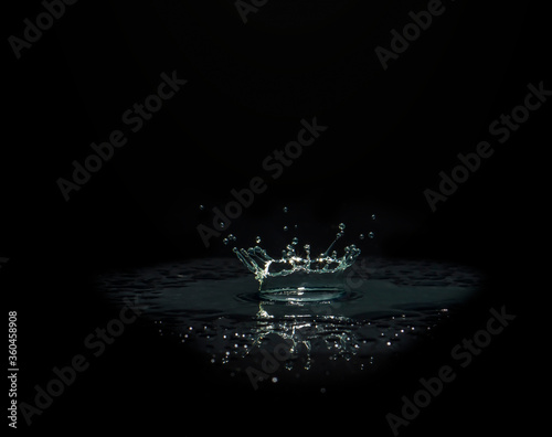Water splashes cause the water distribution into a cylindrical shape. On a black background