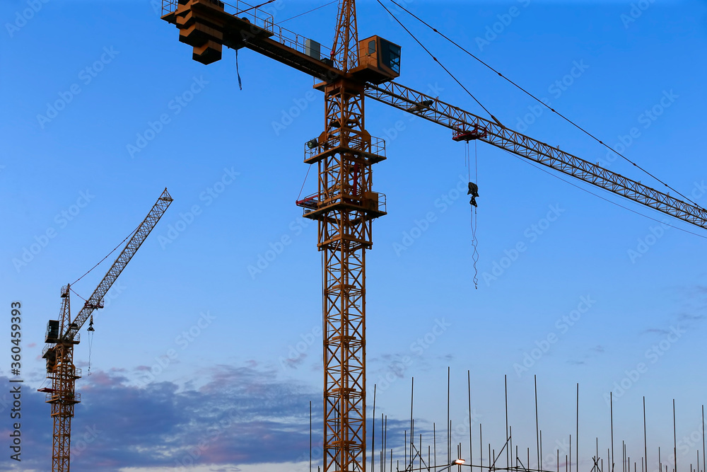 Cranes are silhouetted at a construction site at sunset Cranes are silhouetted at a construction site at sunset