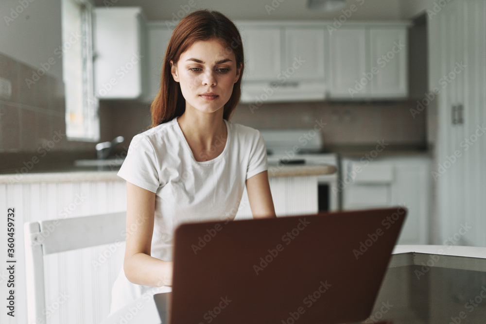 Young woman with a laptop at the table working Young woman with a laptop at the table working