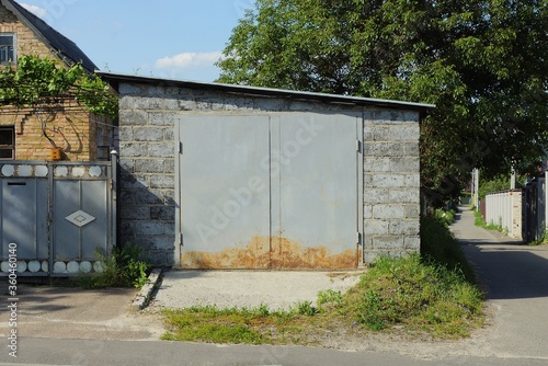 facade of a gray brick garage with an iron gate on a rural street