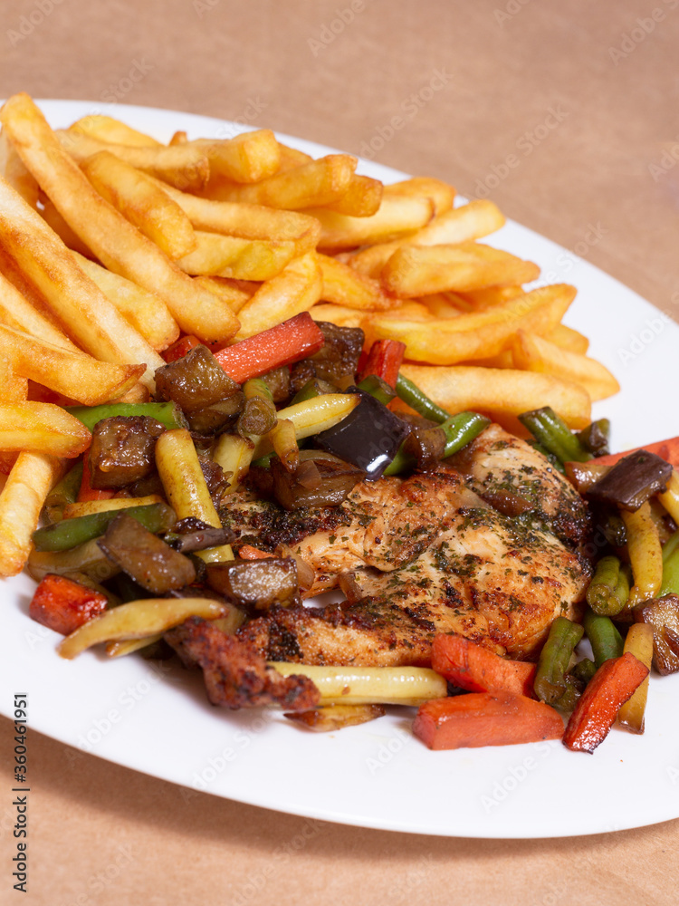 A nice plate of roasted chicken, seasoned with herbs, pepper, salt, oregano, and garlic. Also accompanied by vegetables fried on olive oil.
Accompanied by French fries on a white plate.