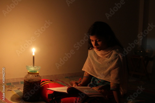 A young girl studying at home with candlelight after electricity load shedding at Dhaka City, Bnagladesh. Blackout. Electricity Problem.