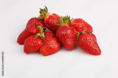 isolated close up top view shot of a bunch of whole and sliced in half vibrant red strawberries on a white background