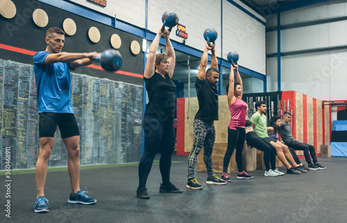 Group of athletes exercising with kettlebells and doing box squats