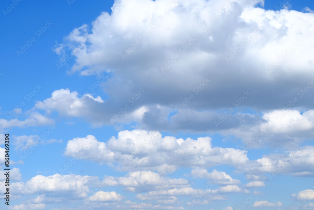 Naklejka premium White fluffy cumulus clouds on a background of blue sky on a sunny day.